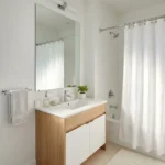 Clean white shower curtain hanging in a bright modern Dubai apartment bathroom